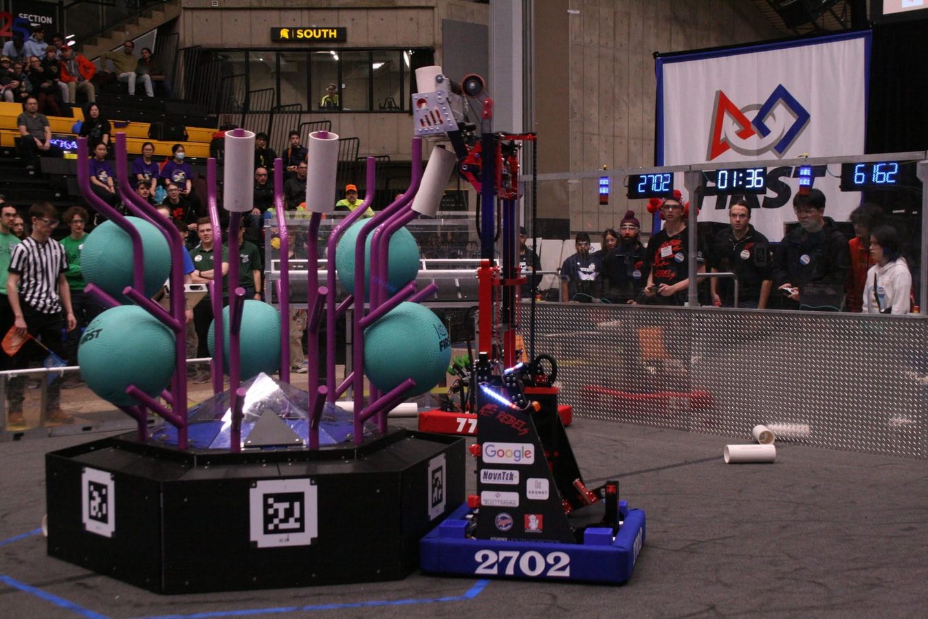 Team 2702's robot beside the scoring structure during a match